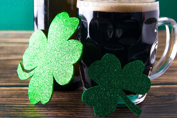 Close-up of two shiny clover leaves on a mug of stout. St. Patrick and stout concept