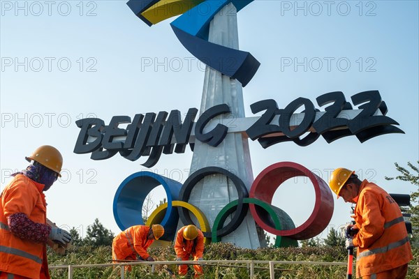 Urban ecological workers work in front of a huge emblem of Beijing 2022 Winter Olympics in Beijing, China. 14-Nov-2021