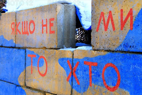 Armed conflict east Ukraine, Ukrainian war. A checkpoint of army in colors of Ukraine flag with patriotic inscription in Ukrainian - If not us, then w