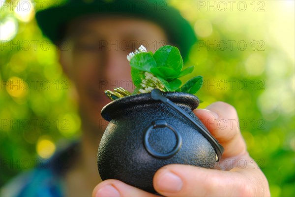 Saint Patrick .clover leaf in bowler hat with gold coins in the hand of a man .Four-leaf clover. Good luck symbol.Irish traditional spring holiday