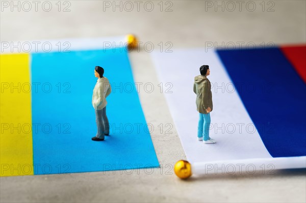 Toy people made of plastic and two flags on an abstract background, a concept on the theme of relations between Russia and Ukraine