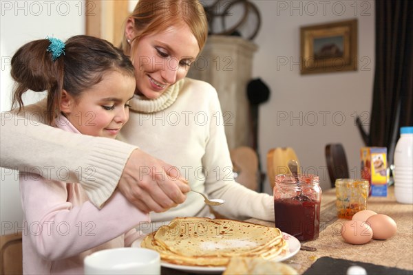 loving mother making crepes with little girl