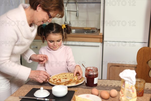 mother preparing crepes with little girl