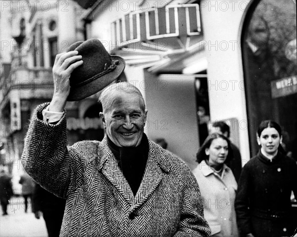 Actor Maurice Chevalier tips his hat on his walk
