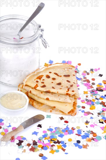 french pancakes wiht pot of butter an sugar on confetti on white background