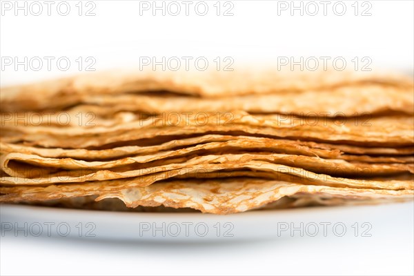 Close up on a stack of crepes (french pancakes) on a plate, white background