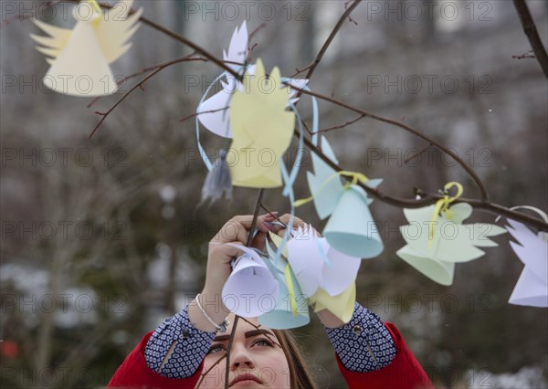 Kyiv, Ukraine. 20th Feb, 2018. A girl hangs the paper cuted angel at a tree near the place where people were killed during the revolution. Ukraine pays tribute to the victims of the 2013-2014 anti-government protests called the Revolution of Dignity, during commemoration events in central Kyiv, Ukraine, Feb. 20, 2018. Over a hundred protesters, the so-called Heavenly Hundred, were killed during the protests as On 20 February 2014, Internal Affairs Minister Vitaliy Zakharchenko announced that he had signed a decree authorising the use of live ammunition against protesters. (Credit Image: