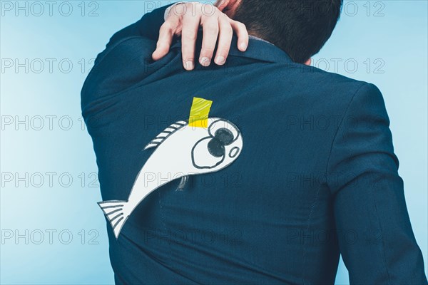 back view of businessman in suit with paper made fish on back, april fools day concept