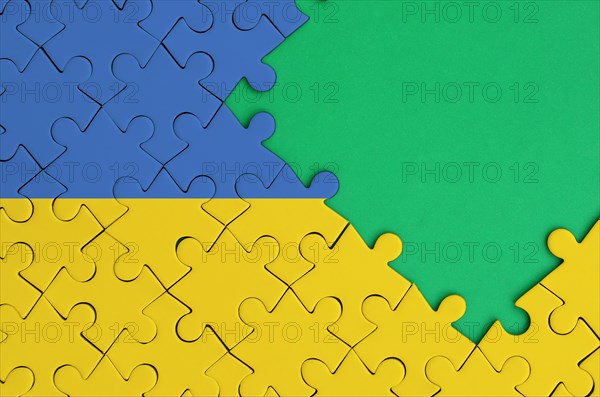 Ukraine flag is depicted on a completed jigsaw puzzle with free green copy space on the right side.