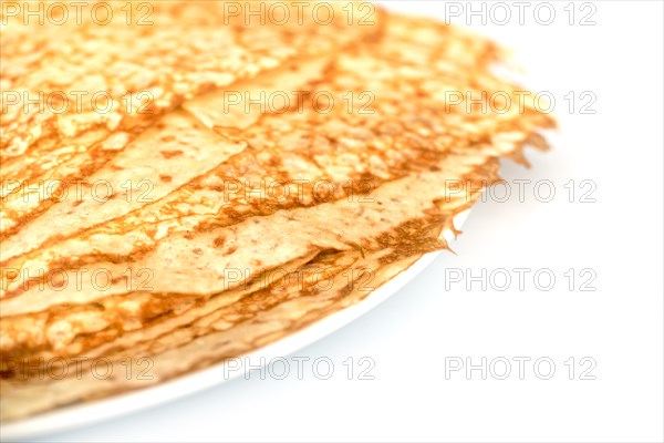 Close up on a stack of crepes (french pancakes) on a plate, white background