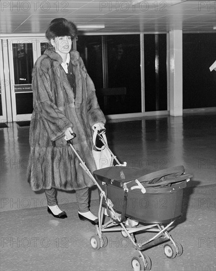Texan model and wife of Rolling Stone Mick Jagger arriving at London's Heathrow Airport with daughter Elizabeth Scarlett in 1985.