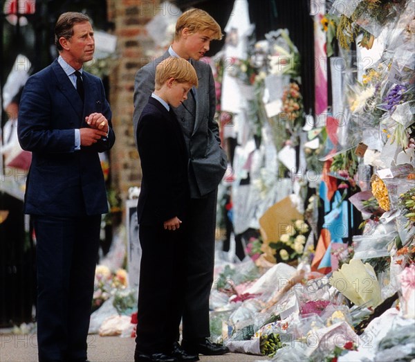 Prince William, Prince Harry and Prince Charles (left to right) examine the floral tributes to the late Princess Diana at Kensington Palace