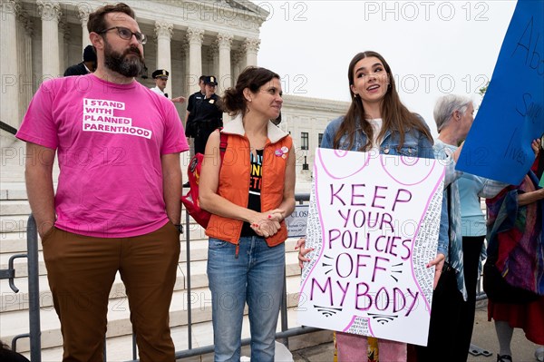 A protester wearing a shirt with words "I stand with Planned Parenthood" stands next to a woman holding a placard reading "Keep your policies off my body" during an abortion related demonstration in front of the Supreme Court.