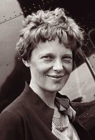 Portrait of Amelia Earhart in front of airplane, 1932.