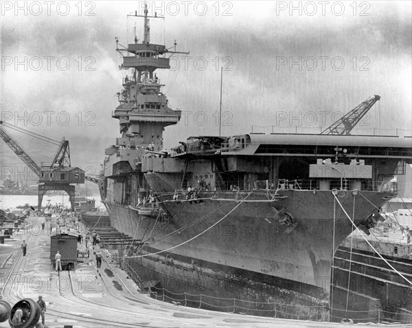 The U.S. Navy aircraft carrier USS Yorktown (CV-5) in Dry Dock No. 1 at the Pearl Harbor Naval Shipyard, 29 May 1942, receiving urgent repairs for damage received in the Battle of Coral Sea. She left Pearl Harbor the next day to participate in the Battle of Midway. USS West Virginia (BB-48), sunk in the 7 December 1941 Japanese air attack, is being salvaged in the left distance.