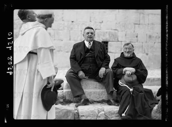 Monsieur & Madame Edouar [i.e., Edouard] Herriot visit to Jerusalem, May 11, 1938. Mr. Herriot & party in front of Ch. [i.e., Church] of Holy Sepulchre showing entrance, Mr. H. seated talking to Fr. Emmanuel Osana
