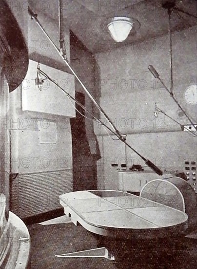 A very early printed photograph of a BBC announcer reading the news.  The BBC began daily radio services in London  in the 1920s on the radio station 2LO. Under the general management of 33 year old John Charles Walsham Reith  the BBC  began to expand its programmes on 14 December 1922. The  first chief engineer was Peter Eckersley. 1927 saw the establishment of British Broadcasting Corporation  by Royal Charter with Reith as its first Director-General.  John Logie Baird  began experimenting  with television broadcasts on BBC frequencies in November 1929..