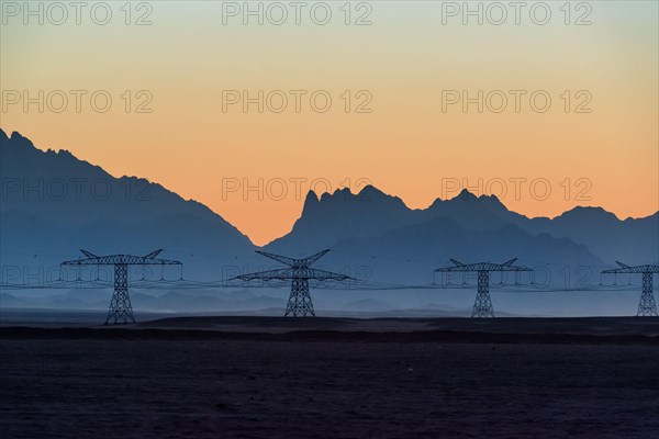 Big powerline in the desert against beautiful evening mountains silhouettes