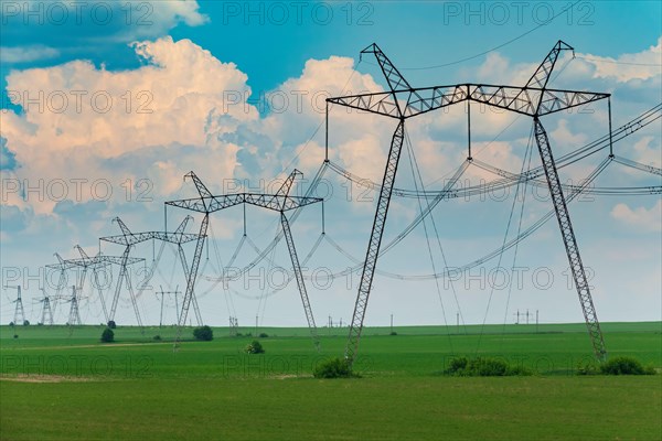 Row of power line support pylons on the countryside field. Energy transition equipment