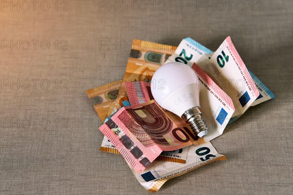 Several euro bills with a light bulb representing the rise in the price of electricity