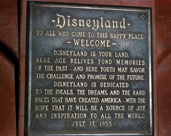 A dedication plaque commemorates the grand opening of the world’s most famous theme park, Disneyland, on July 17, 1955, in Anaheim, California, USA. The metal tablet features a welcome “to this happy place” by Disneyland’s namesake creator, Walt Disney, who read the inscription to thousands of first-day guests and a nationwide audience during a ceremony on live television. Today’s park visitors will find the plaque at the base of the pole flying the American flag at the south end of Main Street, U.S.A.
