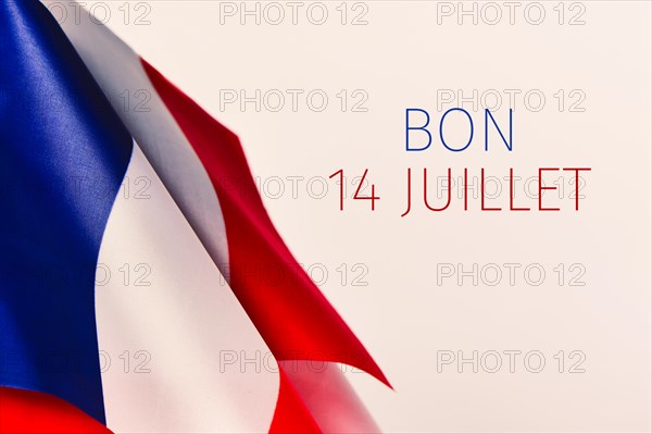 some french flags and the text text bon 14 juillet, happy 14 july, the national day of France written in French, against an off-white background