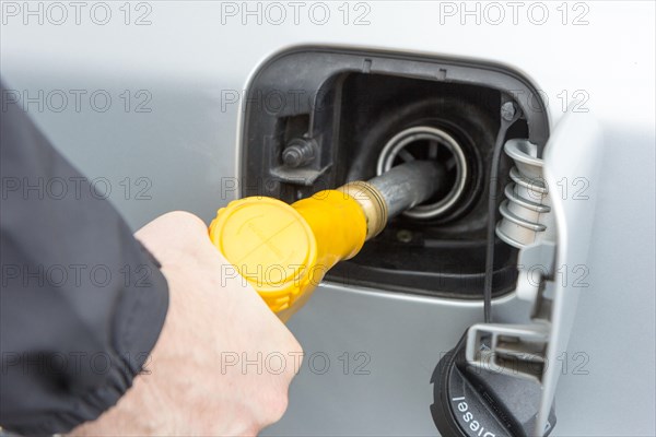 Valenciennes, France. 19 March 2017. A man holding a yellow filling nozzle (gun) and is filling gas to a car.