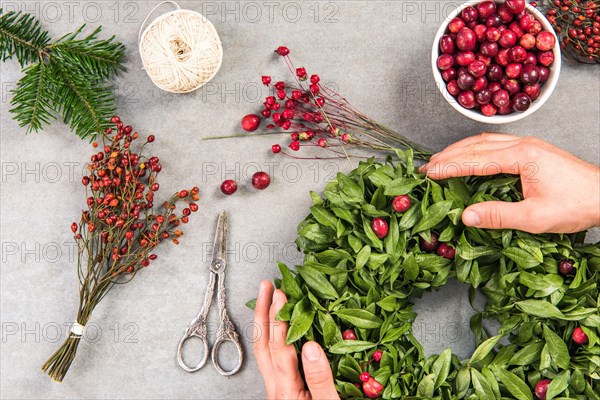 Tattooed florist working on table making Christmas home decoration