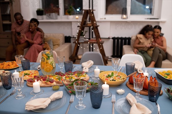 Served festive table with homemade food prepared for Christmas family dinner on background of young African couple and their two children