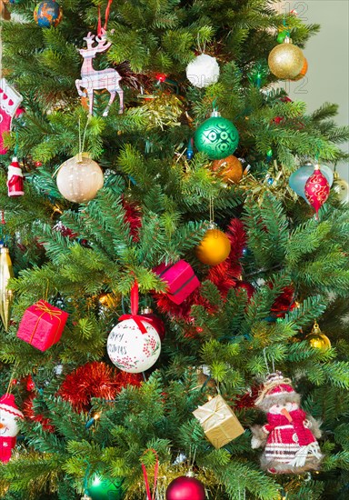 Christmas tree decorated with decorations, ornaments and baubles in a home, UK