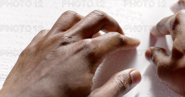 A black man is reading braille