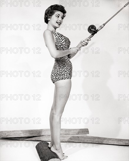 1950s SMILING BRUNETTE WOMAN PINUP WEARING LEOPARD ANIMAL PRINT BATHING SUIT HOLDING FISHING ROD - b9101 CLE003 HARS SHAPE B&W BRUNETTE HAPPINESS CHEERFUL BUILD SEX RECREATION SEDUCTIVE OCCUPATIONS POSING SENSUAL SMILES CONCEPTUAL JOYFUL STYLISH ANGLING COQUETTISH ANIMAL PRINT MODELLING PINUP ATTRACTIVE EXCITING MODELING POSE TIPTOES YOUNG ADULT WOMAN ALLURING BLACK AND WHITE CAUCASIAN ETHNICITY FLIRTATIOUS OLD FASHIONED PROVOCATIVE TEMPTING