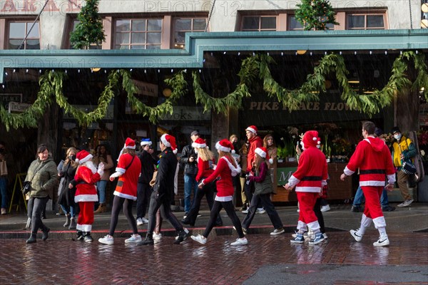 Revelers dressed in holiday themed costumes gather at Pike Place Market during Seattle SantaCon on Saturday, December 11, 2021. The annual pub crawl and fundraiser returned this year after its cancellation in 2020 due to the coronavirus pandemic.