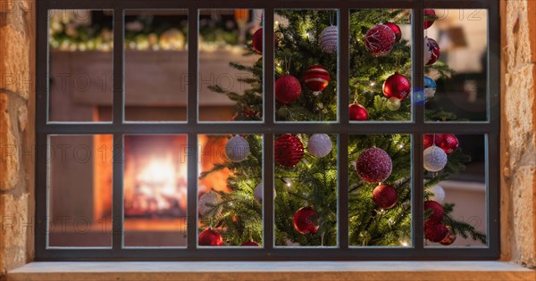 Christmas window. Xmas tree decoration, burning fireplace, winter holiday home interior, view from outdoors