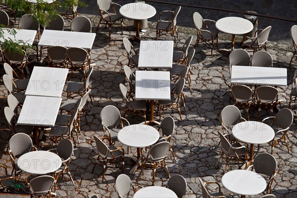 Empty tables at pavement cafe and cobbled pavement in St Emilion, Bordeaux region of France