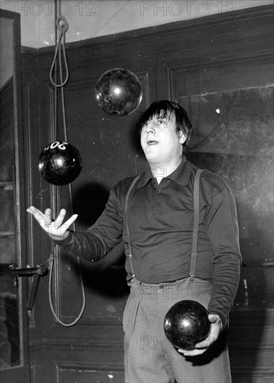 Comedian Raymond Devos juggles weights