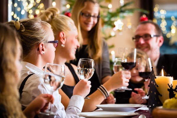 German parents and children toasting with wine and water at Christmas eve dinner