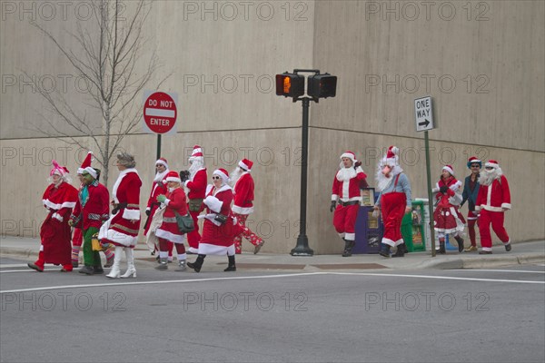 A pack of Santas, Mrs. Clauses and elves cross a street in downtown Asheville around Christmas during the SantaCon event