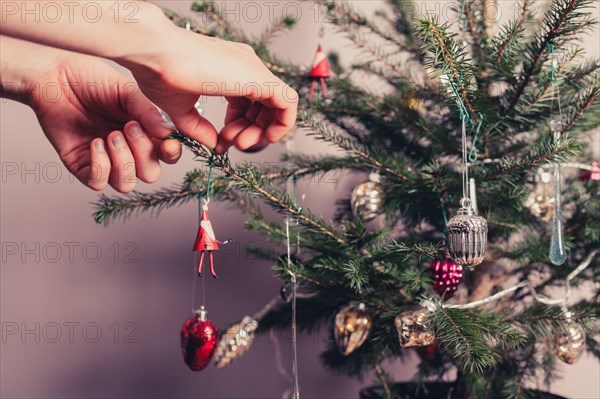 Hands decorating a christmas tree with all kinds of colorful things