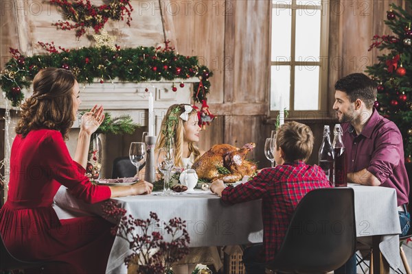 Happy family sitting at holiday table at Christmas time