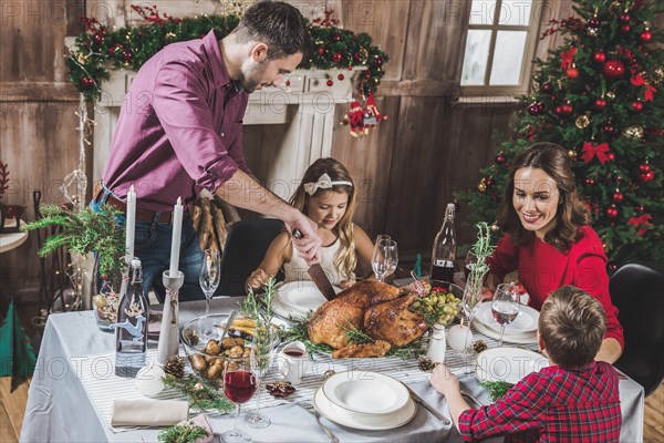 Happy family of four having roasted turkey for Christmas dinner