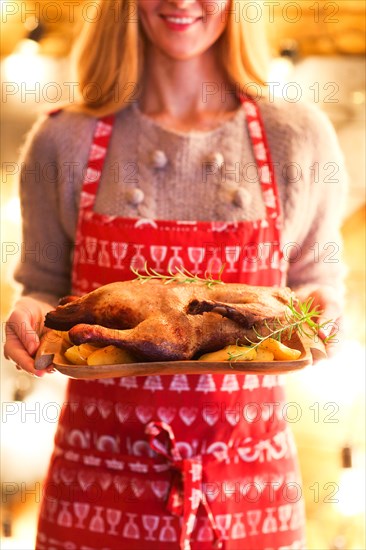 Roast duck and potato on wooden plate in womans hands. Christmas dinner