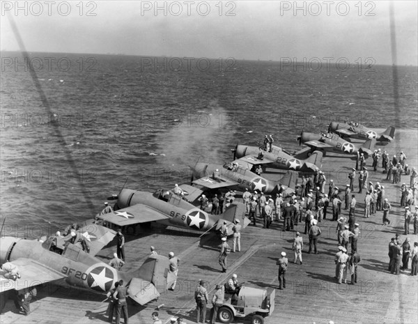 Testing machine guns of Grumman F4F-4 Wildcat fighters aboard USS Ranger (CV-4), while en route from the U.S. to North African waters, circa early November 1942. Note the special markings used during this operation, with a yellow ring painted around the national insignia on aircraft fuselages. Operation Torch