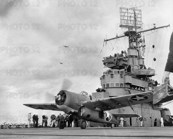 A Grumman F4F-4 Wildcat fighter taking off from USS Ranger (CV-4) to attack targets ashore during the invasion of Morocco, circa 8 November 1942. Note: Army observation planes in the left middle distance; Loudspeakers and radar antenna on Ranger's mast. Operation Torch