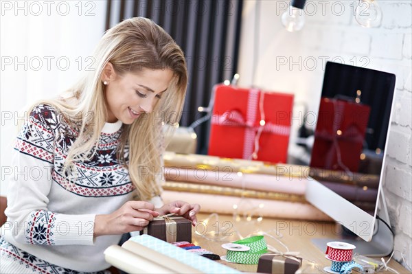 Adult woman at home wrapping Christmas presents