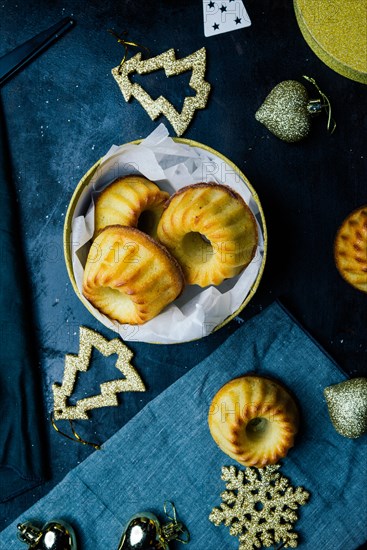 Christmas mini bundt cake and decoration on a board with christmas decoration, a golden package and scissors,top view, flat lay copyspace.