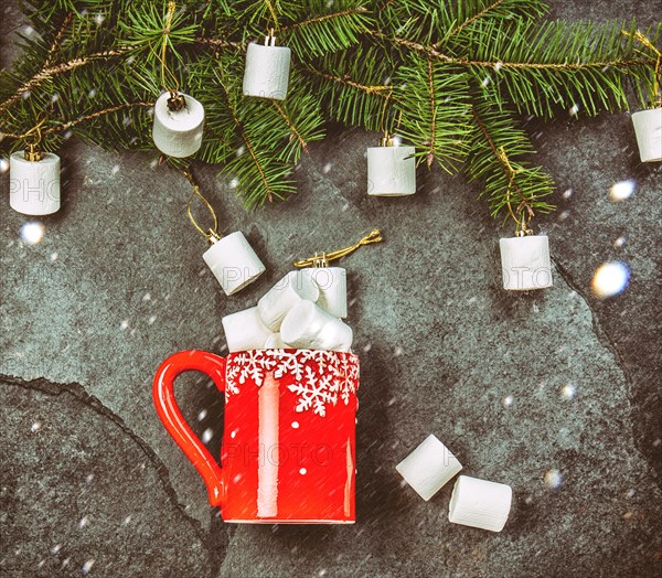 Holiday Christmas Winter concept. Red mug and Christmas tree branch with marshmallow. Black slate background, flat lay composition