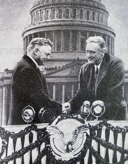 Black and white photo of the new US President Franklin D. Roosevelt (1882-1945) shaking hands in front of the US Capitol Building with the outgoing president, Herbert Hoover (1874-1964). The photo was from Roosevelt's first presidential inauguration on 4 March 1933.