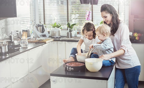 Pretty, brunette mother making cake with her beloved children