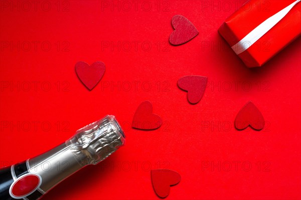 saint valentine day celebration flat lay with a bottle of chapagne and gift on red background
